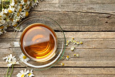 Cam bardakta Aromatik çay ve tahta masada papatya çiçeği. Metin için boşluk