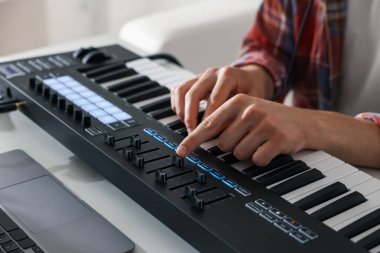 Beyaz masada MIDI klavyesiyle çalışan adam, yakın plan.