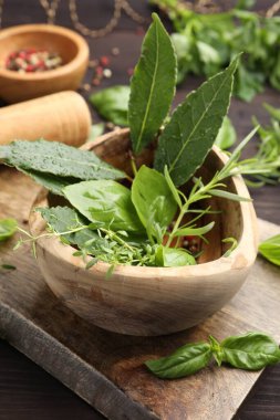 Tahta masada farklı taze otlarla havan topu, yakın plan.