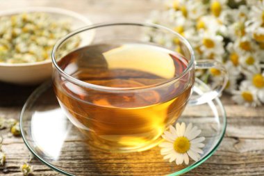 Cam bardakta romatik çay ve ahşap masada papatya çiçekleri, yakın plan.