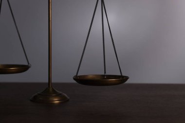 Adaletin terazisi ahşap masada gri arka planda, yakın plan