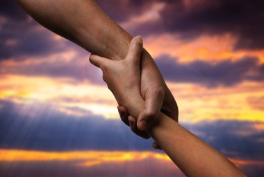 Erkek ve kadın gün batımında gökyüzüne karşı el ele tutuşuyorlar, yakın çekim.