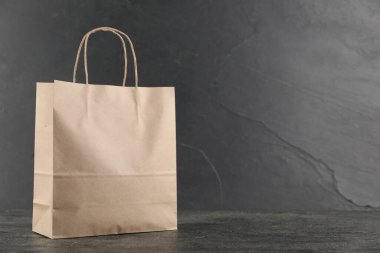 Koyu desenli masa üzerindeki kese kağıdı gri arka planda, yakın plan. Metin için boşluk