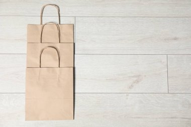 Açık gri ahşap masa üzerinde, düz uzanmış kese kâğıdı torbaları. Metin için boşluk