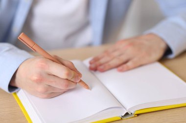 Defterde tahta masada kalemle yazan adam, yakın plan.