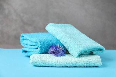 Açık mavi masada yumuşak havlular ve çiçekler