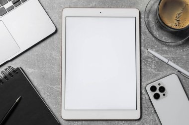 Tablet, akıllı telefon, kahve, kırtasiye ve dizüstü bilgisayar gri masada, düz konum