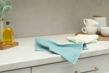 Gri duvarın yanındaki beyaz tezgahta gözleme havluları ve bulaşık takımı.