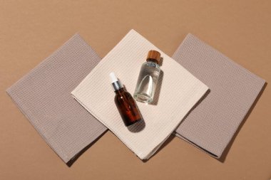 Açık kahverengi arka planda katlanmış waffle havluları ve kozmetik ürünleri şişeleri, düz yatıyordu.