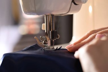 Bulanık arkaplan ve makro görünümde dikiş makinesiyle çalışan kadın