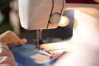 Bulanık arkaplan ve makro görünümde dikiş makinesiyle çalışan kadın