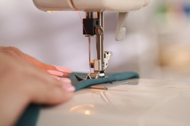 Atölyede dikiş makinesi ve kumaşla çalışan bir kadın.