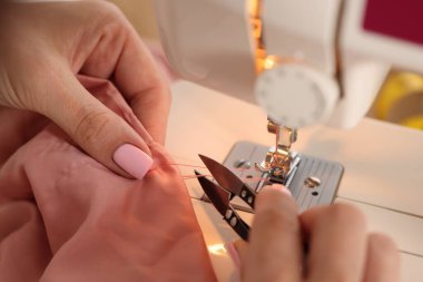 Atölyede dikiş makinesi ve kumaşla çalışan bir kadın.