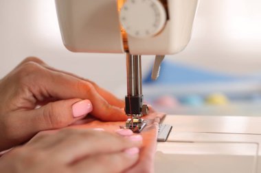 Atölyede dikiş makinesi ve kumaşla çalışan bir kadın.