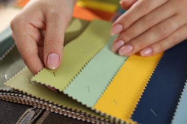 Kadın farklı örnekler arasından kumaşı seçiyor, kapalı alanda, yakın plan.