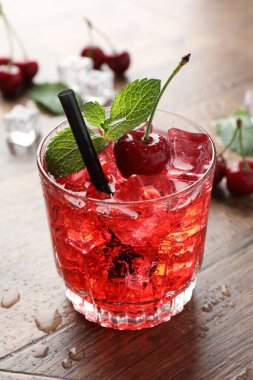 Buzlu vişneli gazoz, böğürtlen ve nane şekeri ahşap masada, yakın plan.