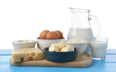 Farklı süt ürünleri ve yumurtalar mavi ahşap masada beyaz arka planda