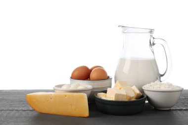 Gri ahşap masada beyaz arka planda farklı süt ürünleri ve yumurtalar