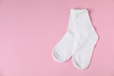 Pembe arka planda bir çift rahat beyaz çorap, üst manzara. Metin için boşluk