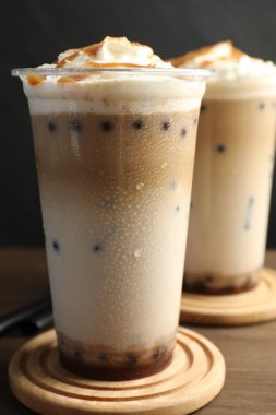 Tahta masada plastik bardaklarda lezzetli sütlü çay, yakın plan.