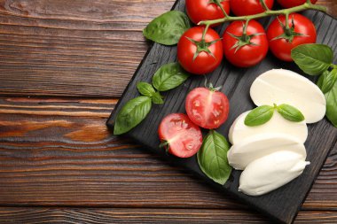 Lezzetli mozzarella peyniri, domates ve fesleğen, ahşap masa, üst manzara. Metin için boşluk
