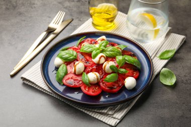 Caprese salatası. Gri masadaki balzamik sirkeyle servis ediliyor. Yakın plan.