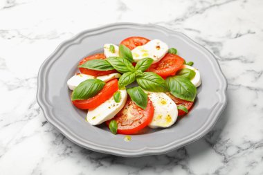 Beyaz mermer masada mozarella, domates, fesleğen ve baharatlı Caprese salatası.