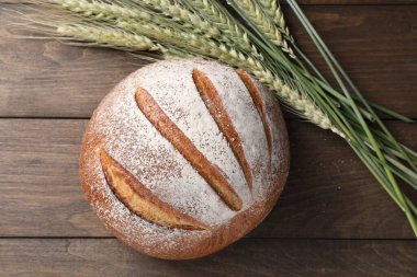Taze ekmek ve yeşil buğday çivileri ahşap masada, düz yerde.