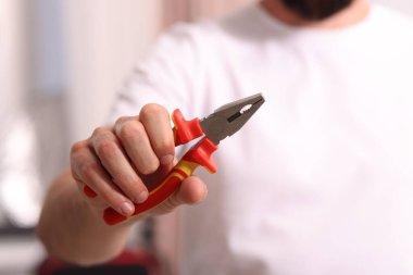 Kapalı mekanda pense giyen adamın yakın görüntüsü.