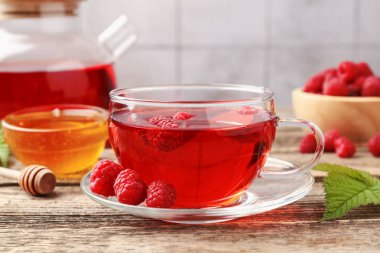 Lezzetli ahududu çayı, böğürtlen ve yapraklar ahşap masada, yakın plan.