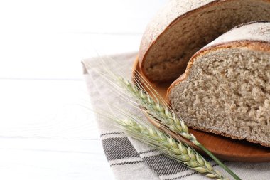 Taze ekmek parçaları ve beyaz ahşap masada yeşil buğday çivileri, yakın plan.