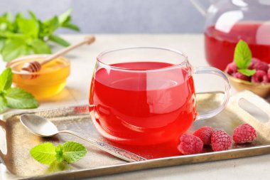 Lezzetli ahududu çayı, böğürtlen, bal ve nane. Açık gri masada, yakın plan.