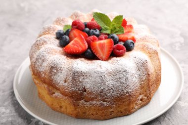 Gri desenli masada pudra şekeri ve böğürtlenli leziz kek, yakın plan.