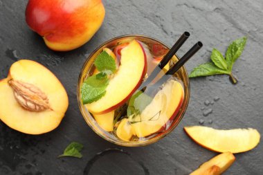 Buzlu şeftali çayı bardakta ve taze meyveler koyu masada, düz yerde.