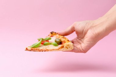 Pembe arka planda lezzetli bir pizza dilimi tutan kadın, yakın plan.
