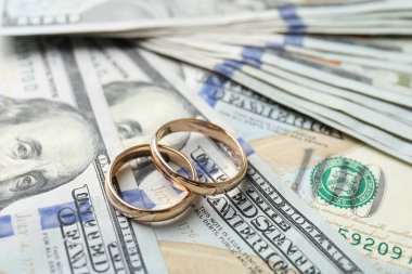 Dolar banknotları üzerinde iki altın alyans, yakın plan.