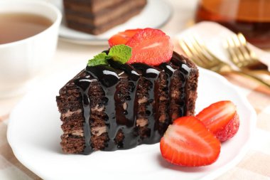 Çilek ve çayla servis edilen bir parça çikolatalı kek, yakın plan.