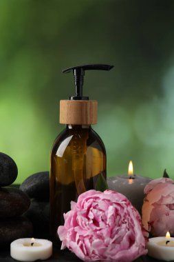 Masanın üzerinde yanan mumlar, çiçekler ve kozmetik ürünler bulunan spa kompozisyonu bulanık yeşil arka plan, yakın plan