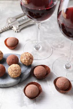 Açık gri arka planda lezzetli trüf şekerleri ve kırmızı şarap, yakın plan.
