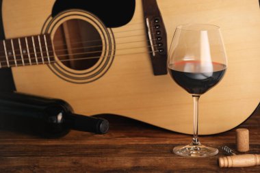 Akustik gitar, şişe ve bir bardak kırmızı şarap.