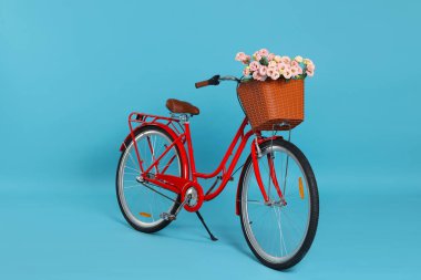 Açık mavi arka planda güzel çiçeklerle dolu bir bisiklet sepeti