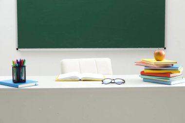 Farklı okul kırtasiyesi, bardaklar ve elma beyaz masada, kapalı alanda.