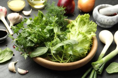 Kasedeki farklı aromatik otlar ve koyu dokulu masadaki ürünler, yakın plan.