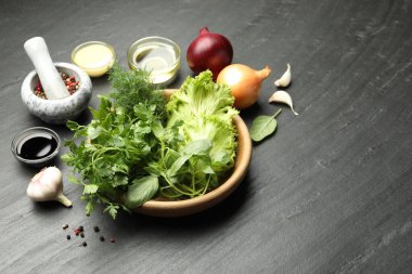 Kasede farklı aromatik otlar, koyu dokulu masada soslar ve baharatlar, yakın plan.