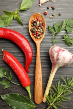 Farklı aromatik otlar, ürünler ve siyah ahşap masa üzerinde biber ve kaşık düz yatıyordu.