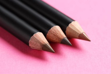 Pembe arka planda farklı kaş kalemleri, yakın plan.