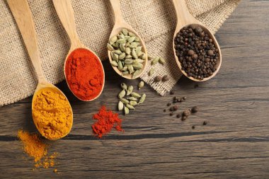 Tahta masada, düz yerde, kaşıklardaki farklı aromatik baharatlar.