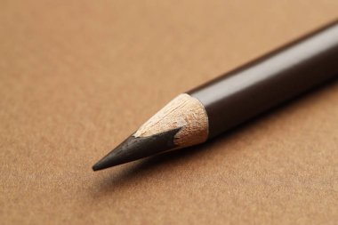 Kahverengi arka planda bir kaş kalemi, makro görünüm