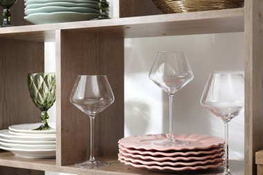 Kapalı alanda yeşil beyaz kapılar ve ahşap raflarda farklı tabaklar ve bardaklar var.