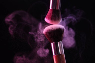 Siyah arkaplandaki neon ışıklarıyla göz farları renginde makyaj fırçaları, yakın plan